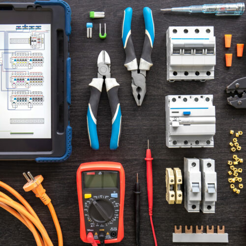Flat lay composition with electrical tools and digital tablet on wooden background.