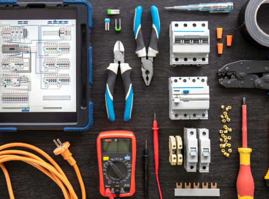Flat lay composition with electrical tools and digital tablet on wooden background.