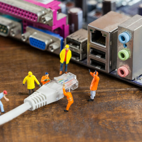 Conceptual image of miniature engineer and worker plug-in lan cable to computer