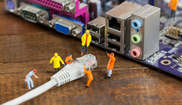 Conceptual image of miniature engineer and worker plug-in lan cable to computer