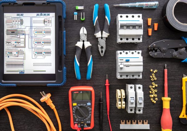 Flat lay composition with electrical tools and digital tablet on wooden background.
