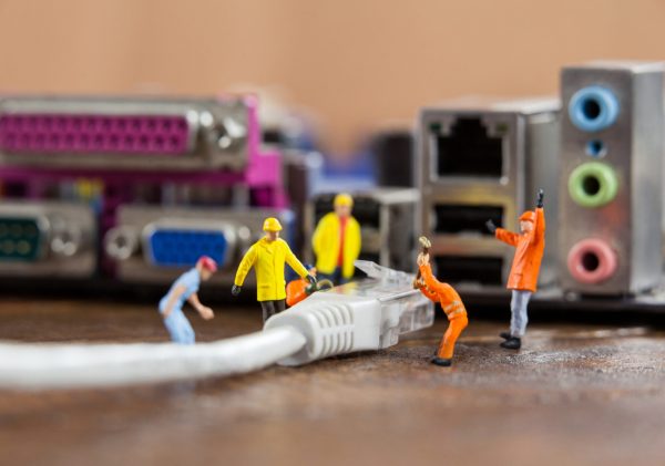 Conceptual image of miniature engineer and worker plug-in lan cable to computer